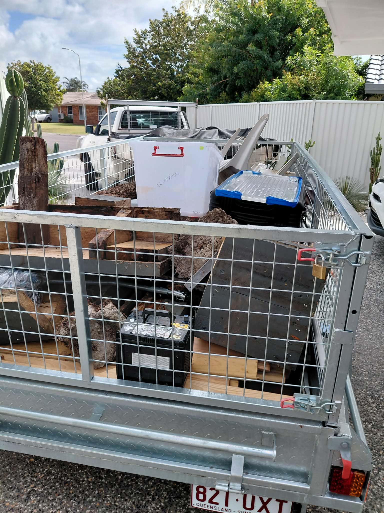 Caged trailer loaded with household items, timber and rubbish for removal