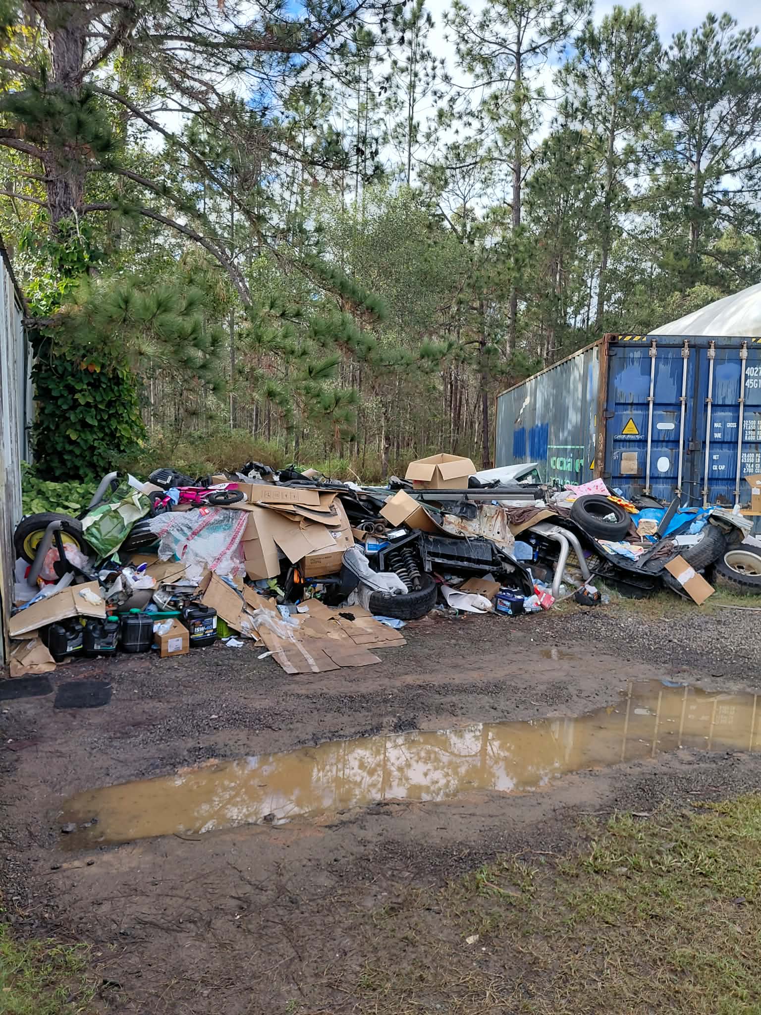 Large rubbish pile ready for removal beside a shipping container